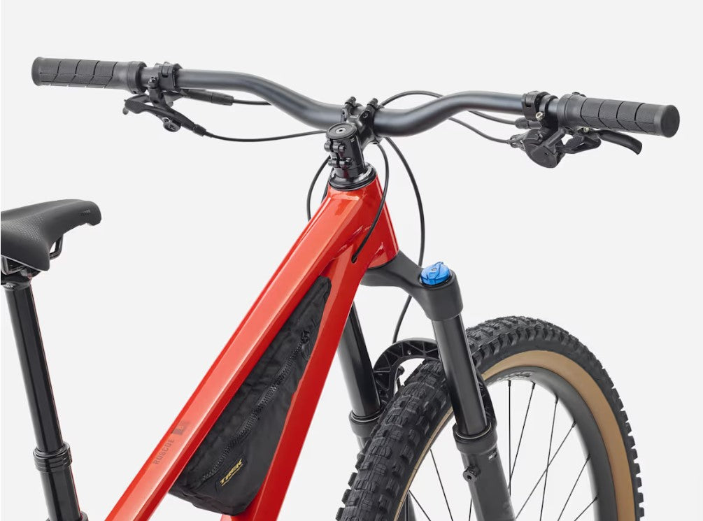 Close up view of handlebars of red Trek Roscoe mountain bike with black components with white background.