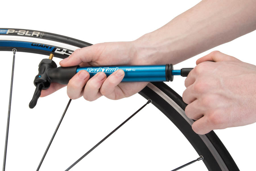 Blue and black Park Tool Mini Air Tool Pump being used on a bicycle wheel.