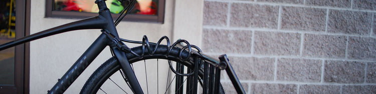 A bike is locked to a bike rack next to a gray brick building.