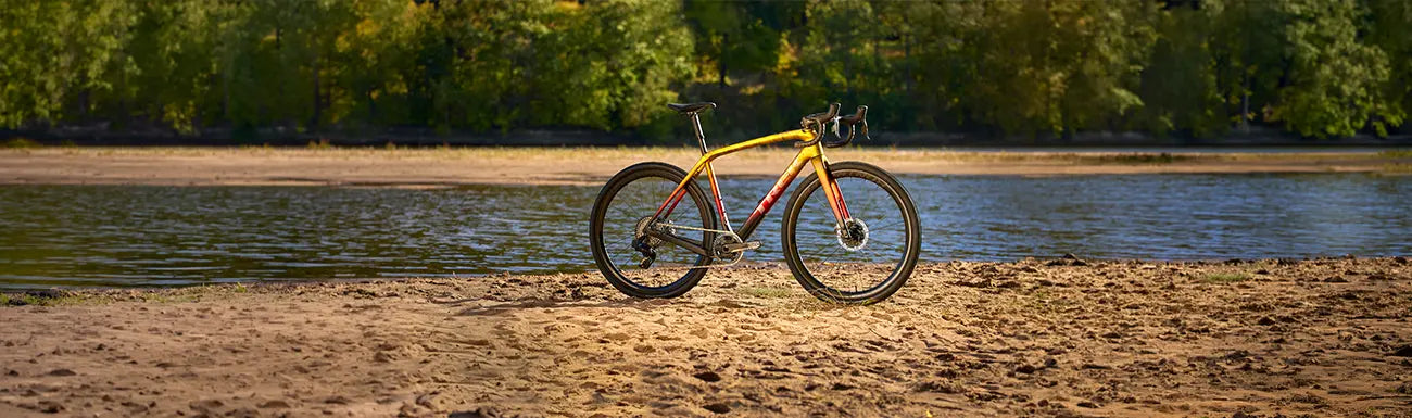 Image of a yellow, red and black Trek Road Bike on a beach.