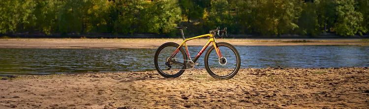 Image of a yellow, red and black Trek Road Bike on a beach.