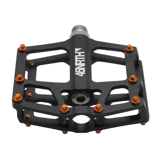 Angled top view of the 45NRTH Heiruspecs 9/16 Inch Aluminum Black Platform Pedal with orange studs against a white background.