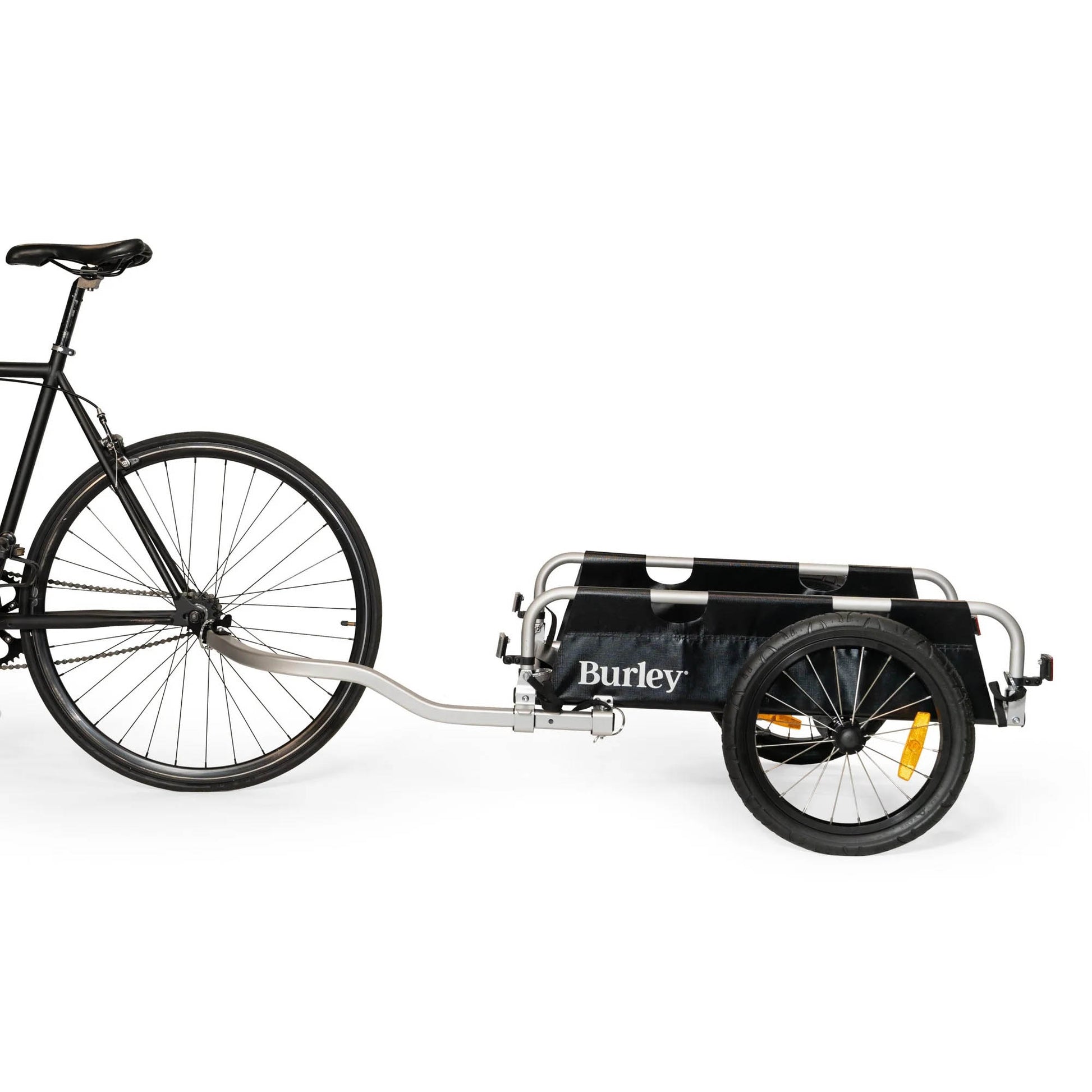Side view of the Burley Flatbed Cargo Trailer, shown attached to a bicycle, on a white background.