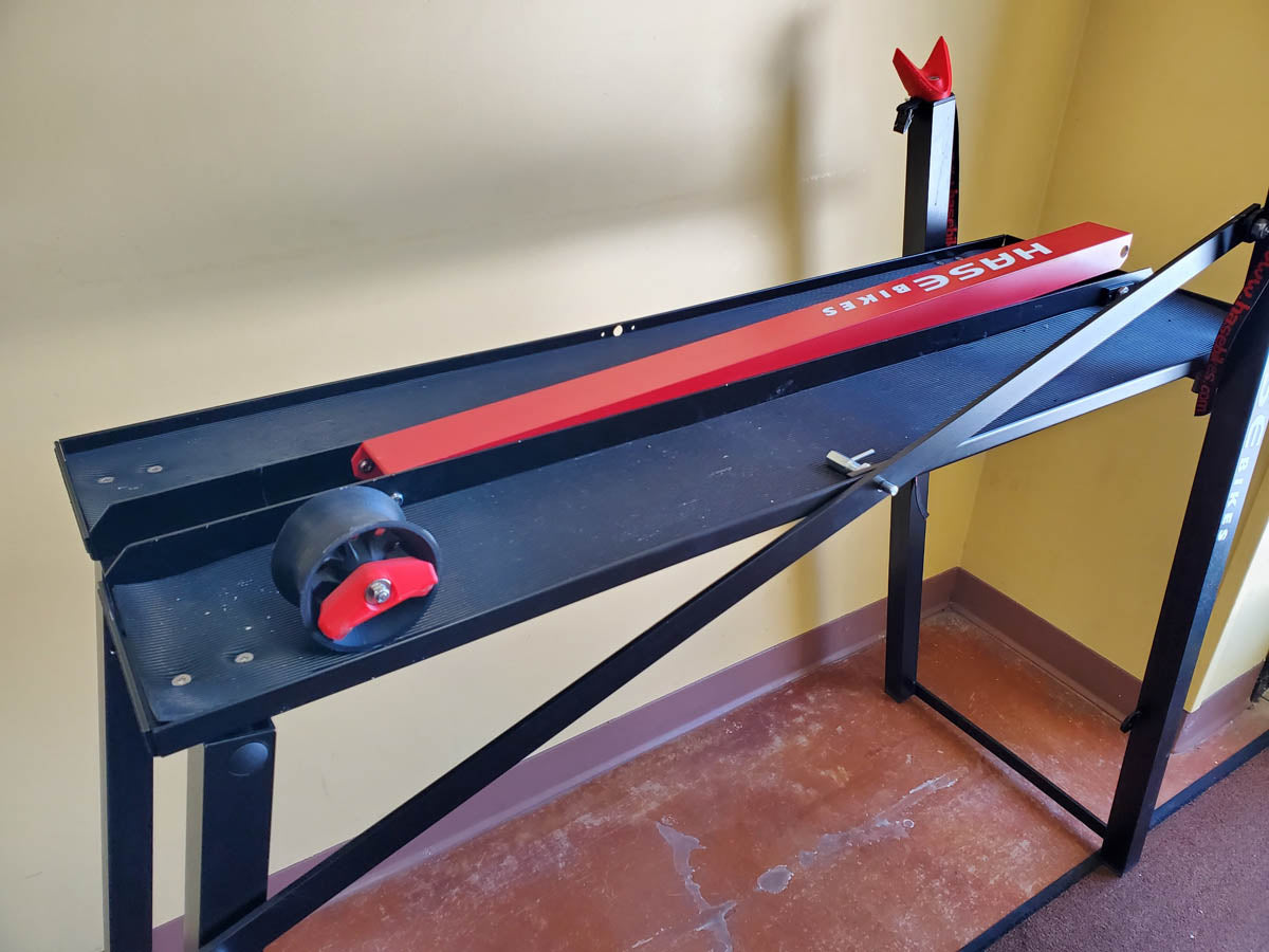 Black and red Hase work stand for recumbent trikes with red arm folded.