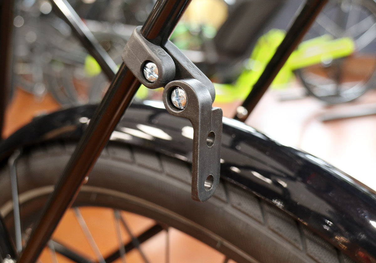 Black plastic light mount installed on the support stays of a black bicycle rack. 
