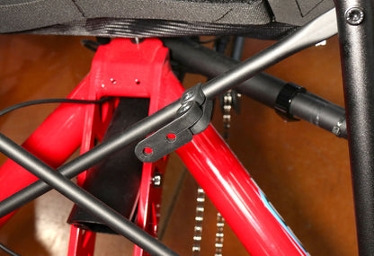 Black plastic bracket secured to seat stay of a recumbent trike, bracket has two open holes to install items to. 