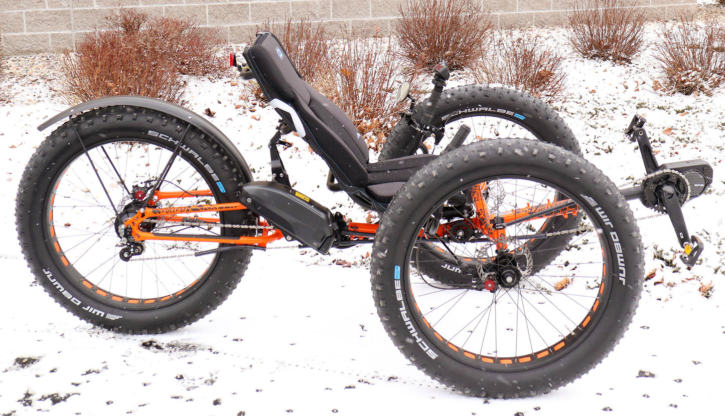 Right profile view of orange ICE full fat recumbent trike in the snow.