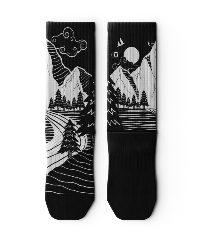 Black and White socks laying flat, with mountain and forest scene