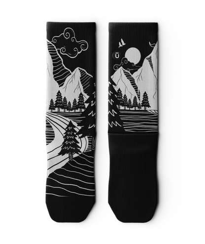 Black and White socks laying flat, with mountain and forest scene