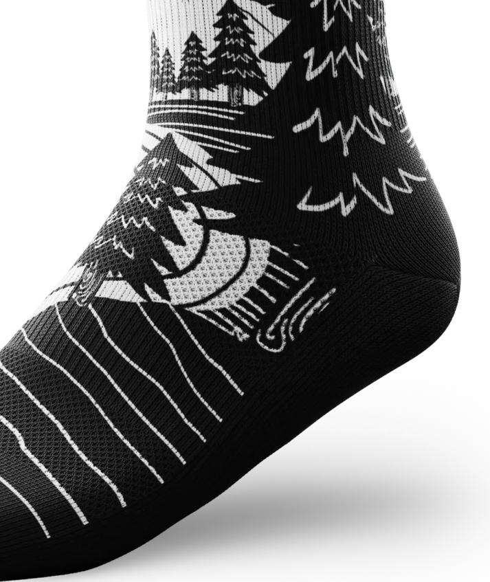 Ankle portion of black and white socks with mountain and forest scene