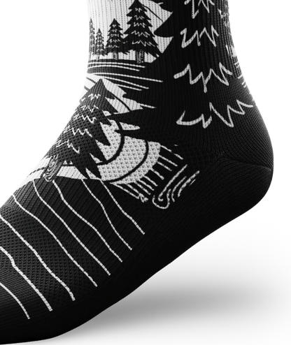 Ankle portion of black and white socks with mountain and forest scene