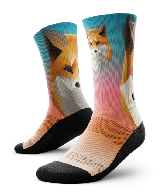 Multicolored pair of socks with geometric sock head. Background of sock is teal blue at the top fading to light orange near toes. Sole of socks is black