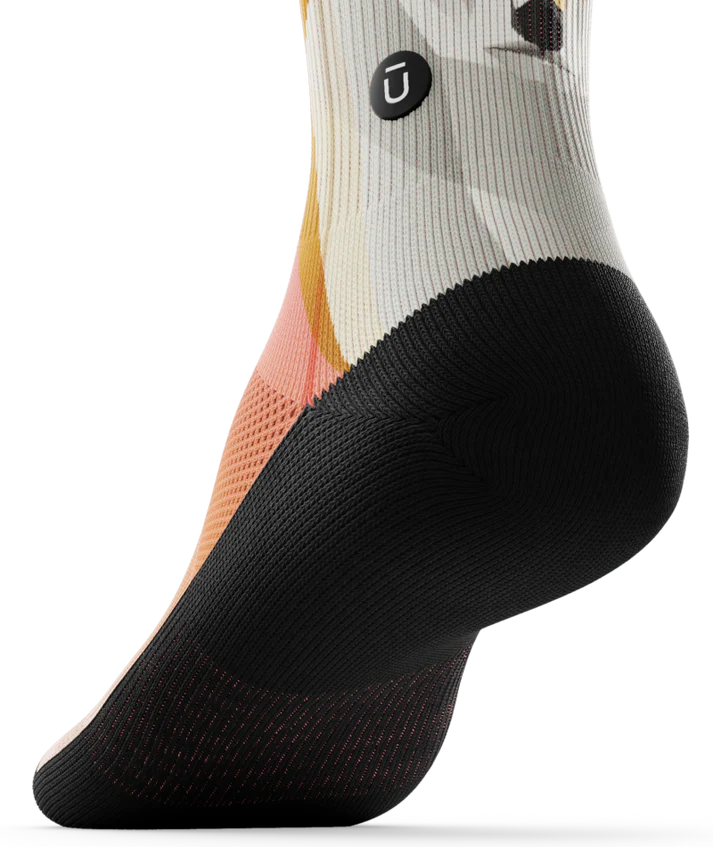 Bottom black sole view of Multicolored pair of socks with geometric sock head. 