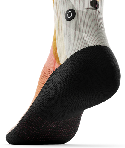 Bottom black sole view of Multicolored pair of socks with geometric sock head. 