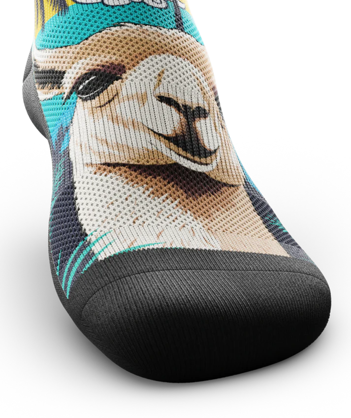 Front toe view of sock with with ocean sunset, black palm trees, and heads of llamas on main part of sock.