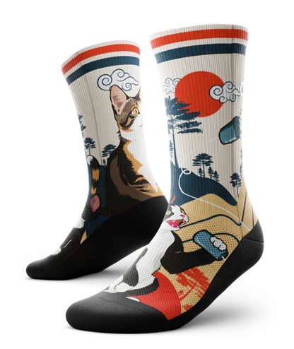 Multicolored pair of socks with black and white cat talking into a can connected with a string to another calico cat.  Asian inspired background of trees and sun. Black soles