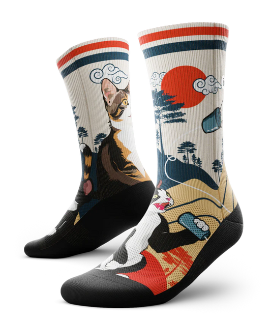 Multicolored pair of socks with black and white cat talking into a can connected with a string to another calico cat.  Asian inspired background of trees and sun. Black soles