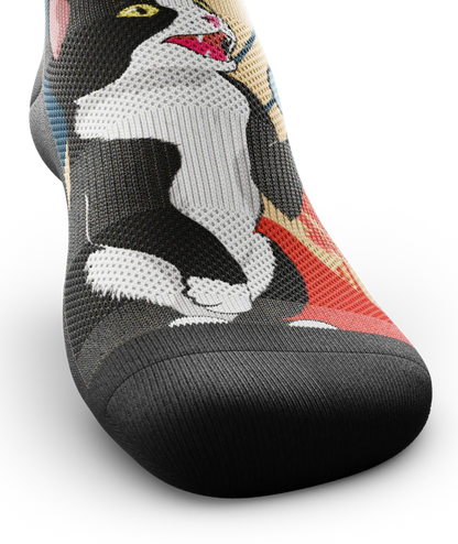 Top toe view of a Multicolored sock with black and white cat talking into a can.  Black soles