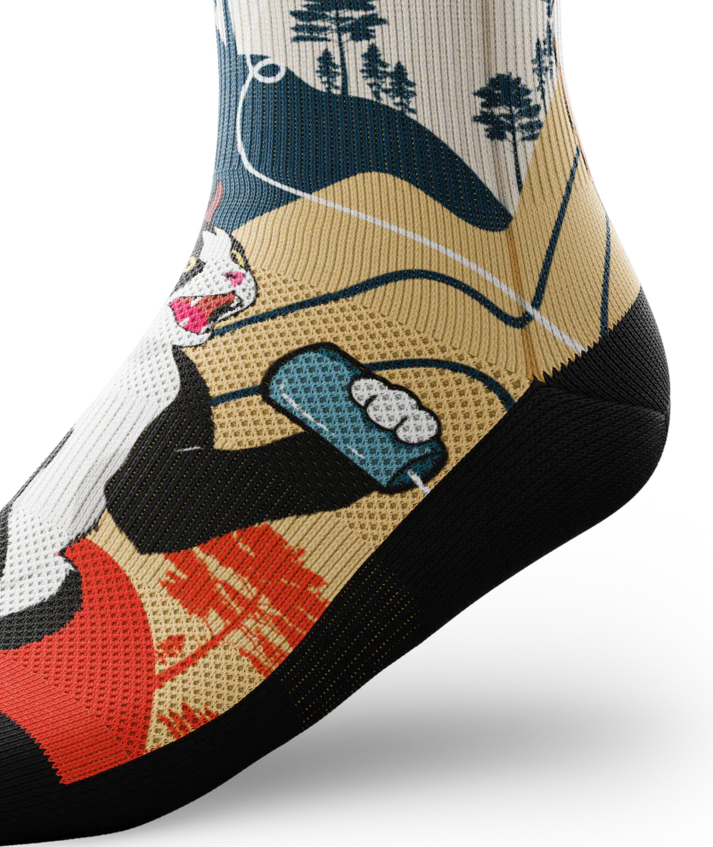 Ankle side view of multicolored socks with black and white cat talking into a can connected with a string to another calico cat.  Asian inspired background of trees and sun. Black soles