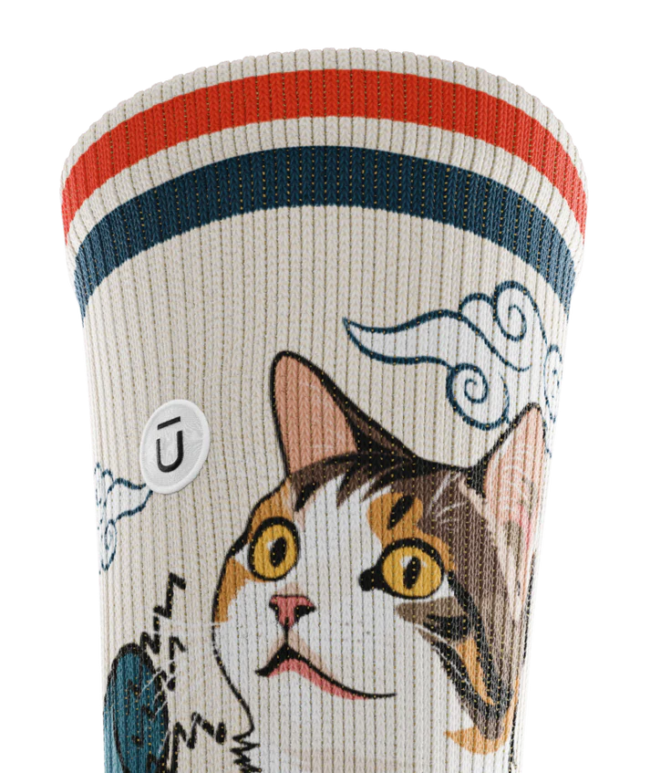 Top cuff view of sock. Red and blue stripe along top of cuff, calico cat on cuff.  Small white circular patch with Outway logo on top third of cuff. 