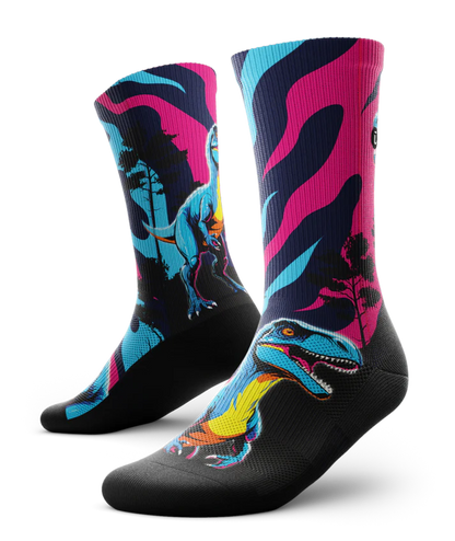 Multicolored pink, blue and black pair of socks with velociraptors, black trees and black soles. 