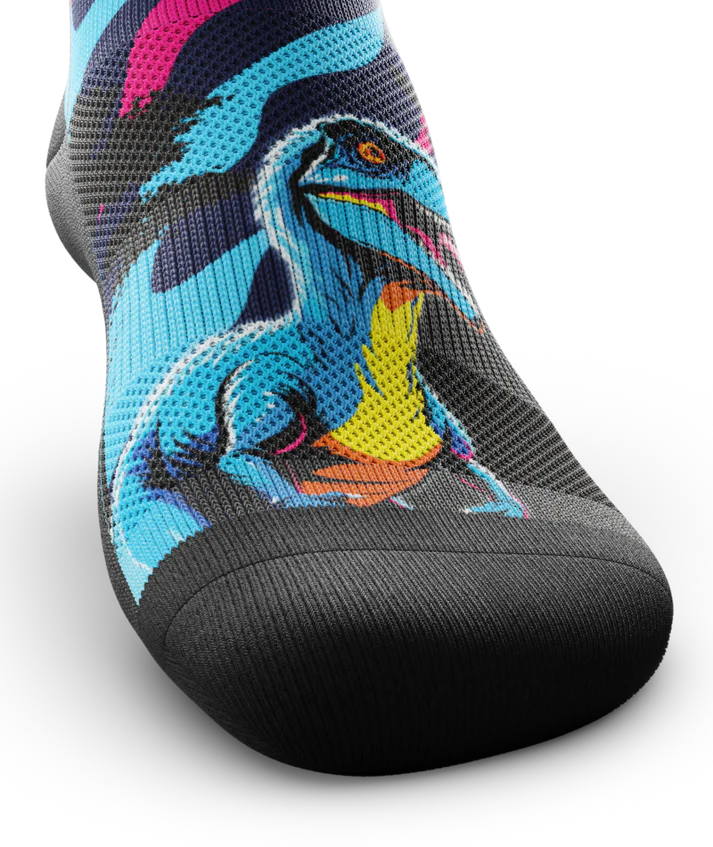 Top toe area of sock with blue yellow and orange velociraptor across top of sock .  Toe and sole are black. 