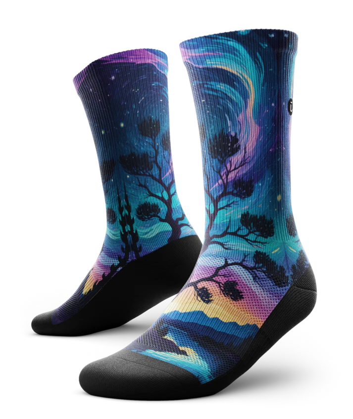 Multicolored pair of socks with colorful northern lights in the ski over a mountain lake with trees silhouetted.  