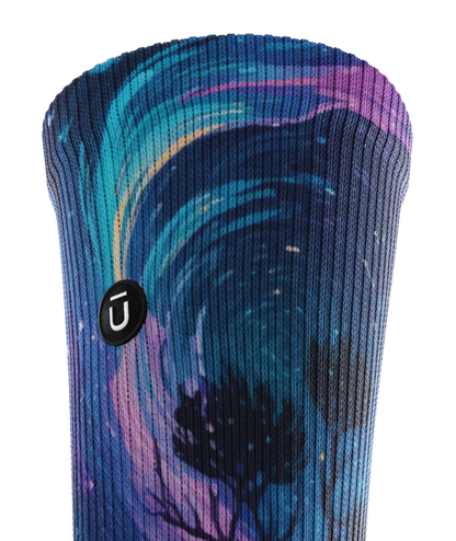 Top cuff view of multicolored sock with colorful northern lights in the ski over a mountain lake with trees silhouetted.  Small black circular patch with Outway logo on op third of cuff. 