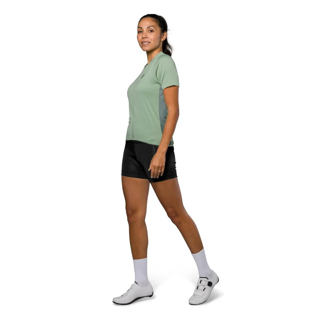 Studio image of a model wearing the Pearl Izumi Sugar Jersey in light green, with darker green panels of fabric along the sides. 