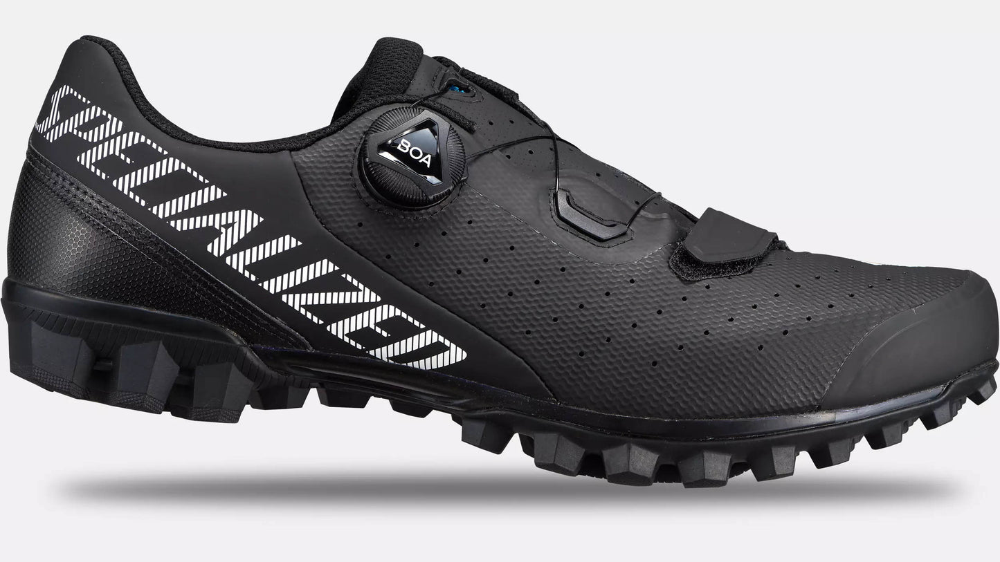 Studio image of the outer side of a Specialized Recon 2.0 black mountain bike show with white Specialized lettering extending from the top heel of the shoe down to the arch of the shoe, a black hook and loop closure across the toe and a black BOA dial.