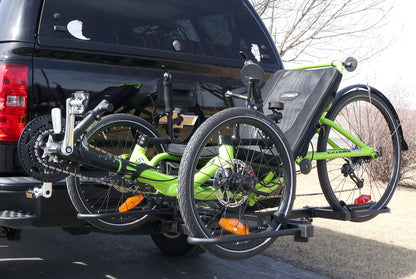Angled view of the Sunlite HRT-100 Trike Auto Rack for 2-inch Receivers mounted on the hitch on a pickup truck with a green Catrike on the rack in an outdoor setting.