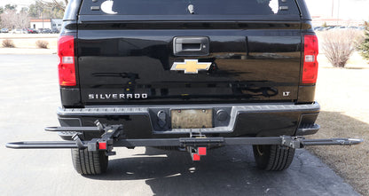 Rear view of the Sunlite HRT-100 Trike Auto Rack for 2-inch Receivers mounted on the hitch on a black pickup truck in an outdoor setting.