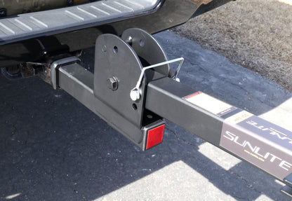 Close up view of the folding mechanism on the Sunlite HRT-100 Trike Auto Rack for 2-inch Receivers mounted on the hitch on a black pickup truck in an outdoor setting.