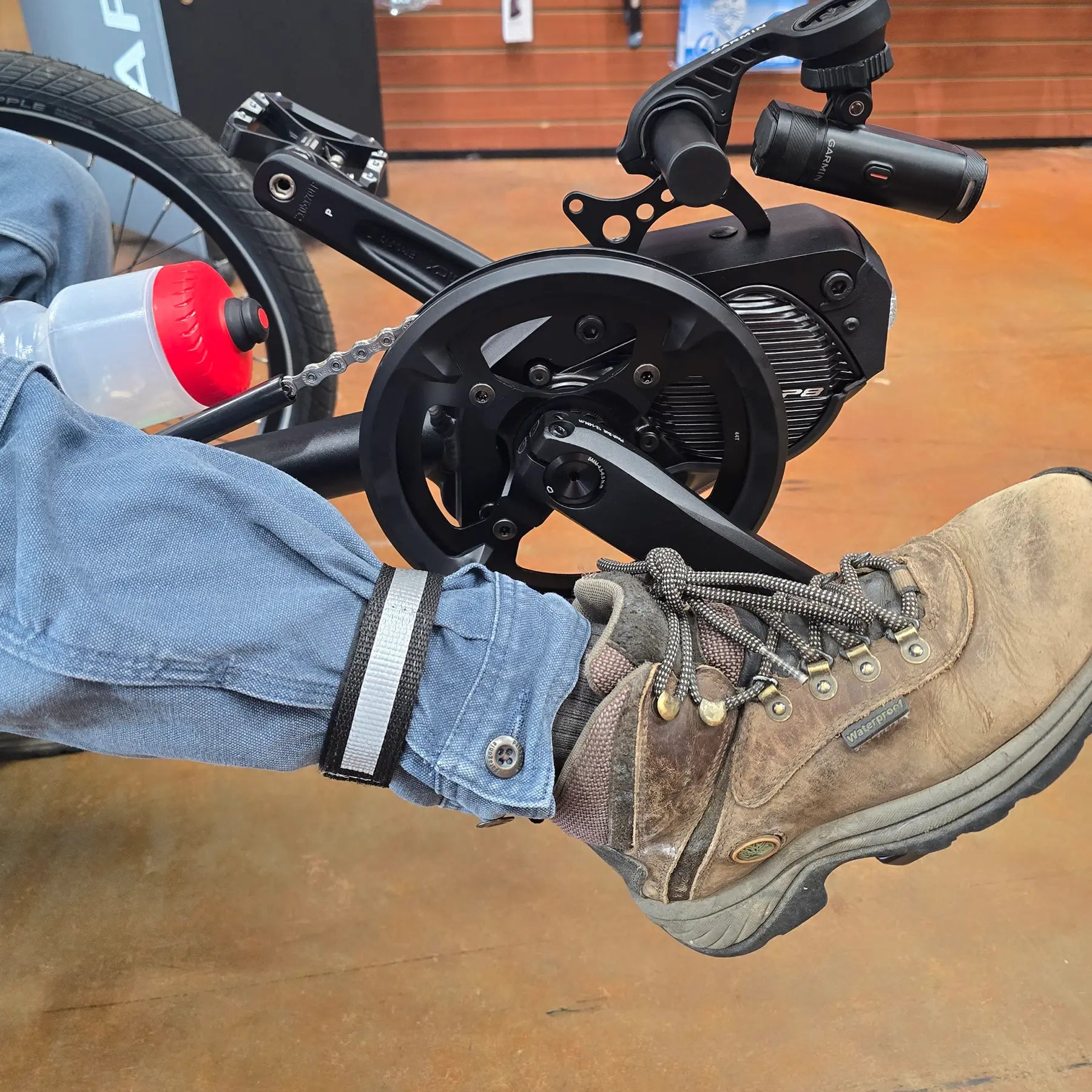 Closeup view of the Aardvark Ankle Biters Reflective Leg Band Black Single on a persons right leg while sitting on a trike.