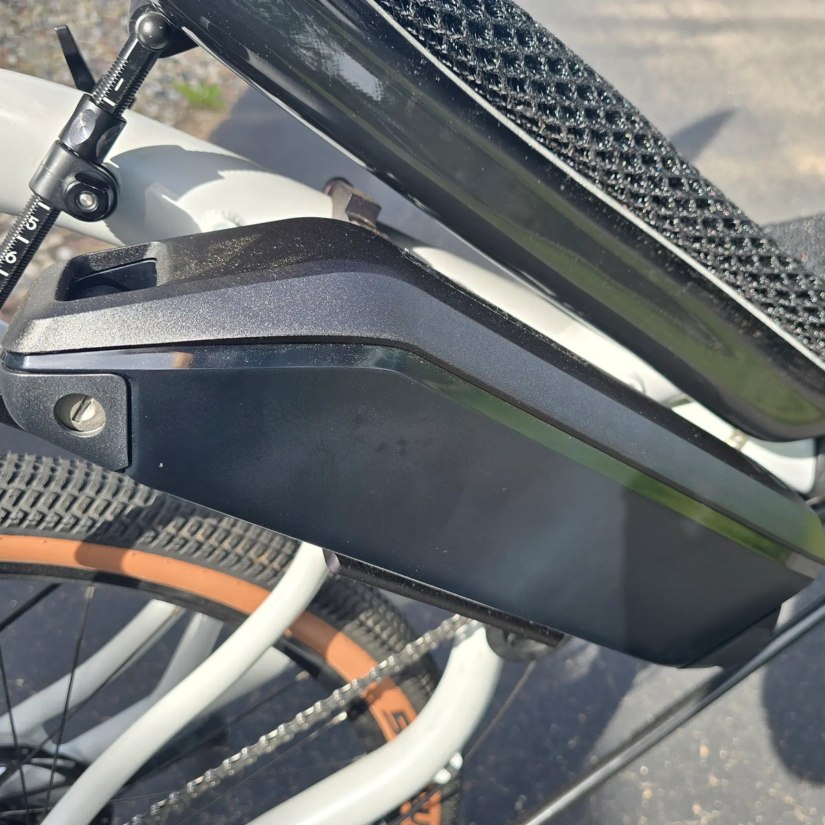 Closeup view of thebattery and seat pad on the Azub Demo Six Bosch Performance CX Dynamic Grey Recumbent Bike in an outdoor setting.