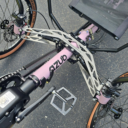 Closeup view of the front suspension and folding hinge on the Azub Demo Ti-Fly 20 Enviolo Shimano EP6 Pastel Violet Recumbent Trike in an outdoor setting.