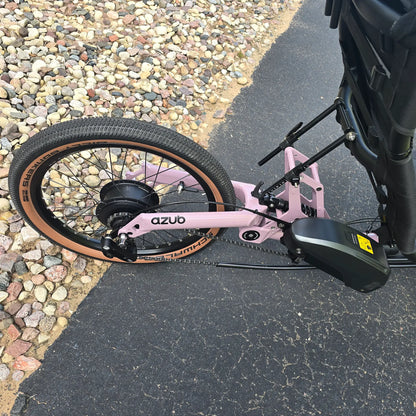 Closeup view of the rear suspension, battery and rear wheel on the Azub Demo Ti-Fly 20 Enviolo Shimano EP6 Pastel Violet Recumbent Trike in an outdoor setting.