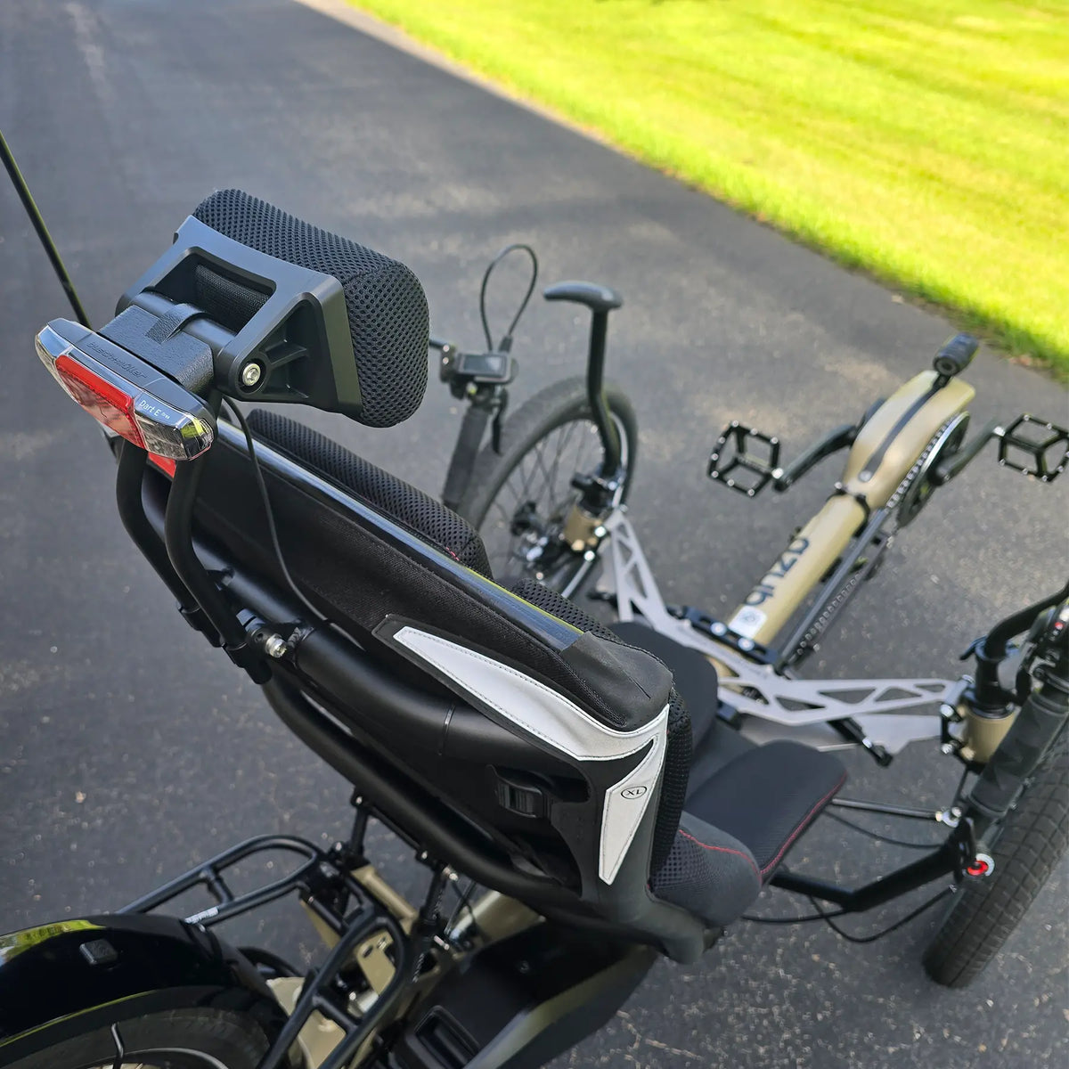 Closeup view of the neckrest and taillight on the Azub Demo Ti-Fly 26 Bosch Performance CX Dark Sand Recumbent Trike in an outdoor setting.