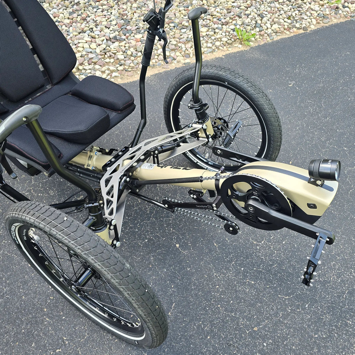 Closeup view of the headlight, Bosch motor, quick adjust and front suspension on the Azub Demo Ti-Fly 26 Bosch Performance CX Dark Sand Recumbent Trike in an outdoor setting.