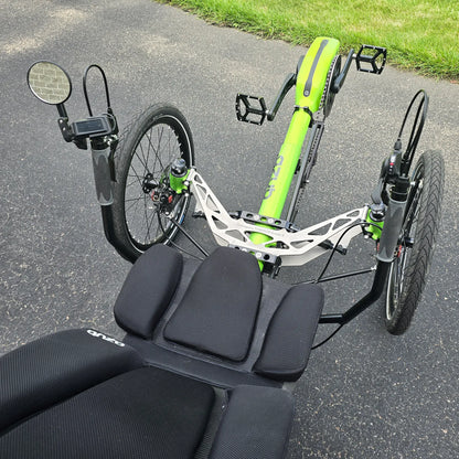 Closeup view of the mirror, handlebars with controls and the front suspension on the Azub Demo Ti-Fly 26 Bosch Performance CX Lime Green Recumbent Trike in an outdoor setting.