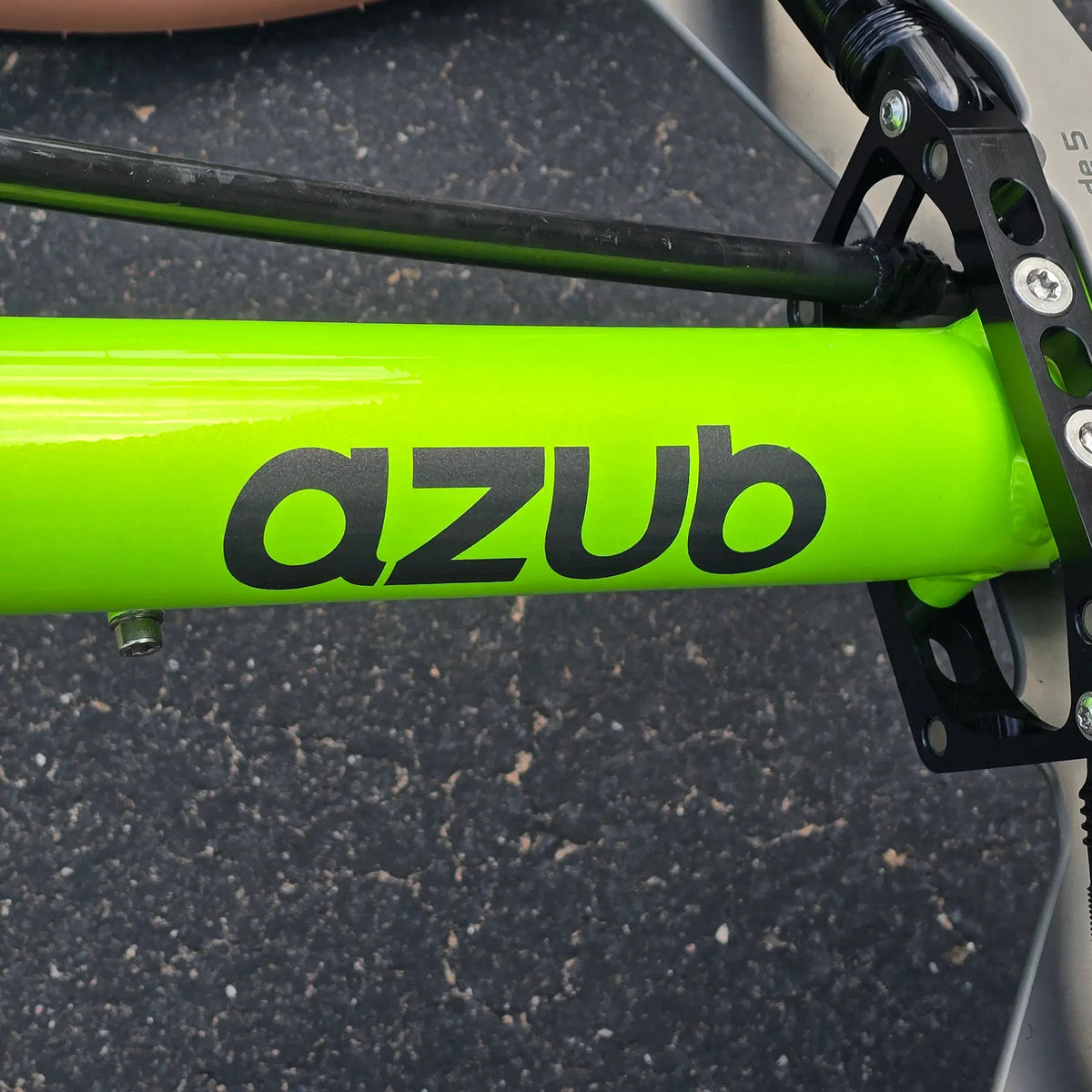 Closeup view of theAzub logo in black  on the Azub Demo Ti-Fly X Rohloff E14 Bosch Performance CX Dual Battery Lime Green Recumbent Trike in an outdoor setting.