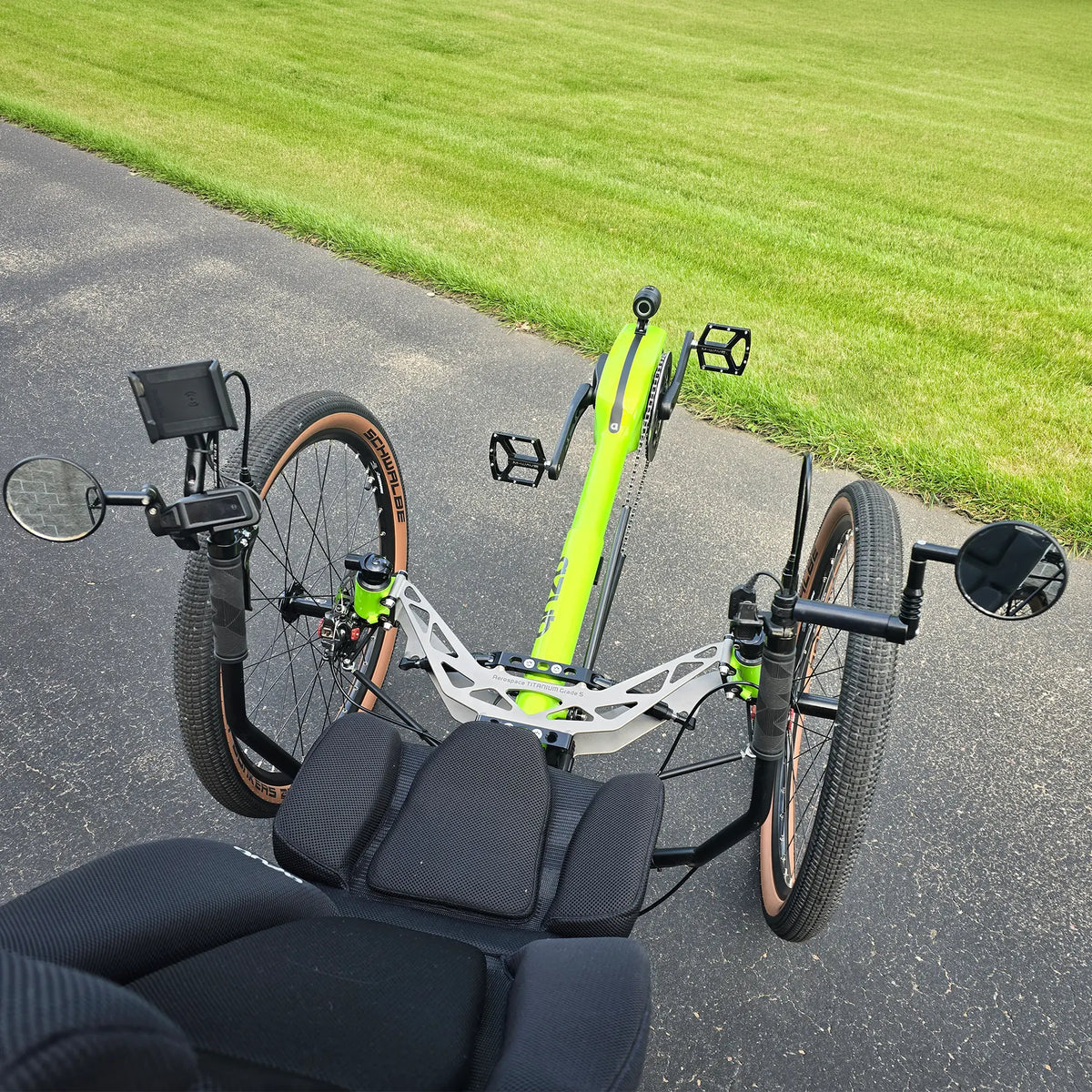 Closeup view of the handlebars with controls, dual mirros, phone holder and front suspension on the Azub Demo Ti-Fly X Rohloff E14 Bosch Performance CX Dual Battery Lime Green Recumbent Trike in an outdoor setting.