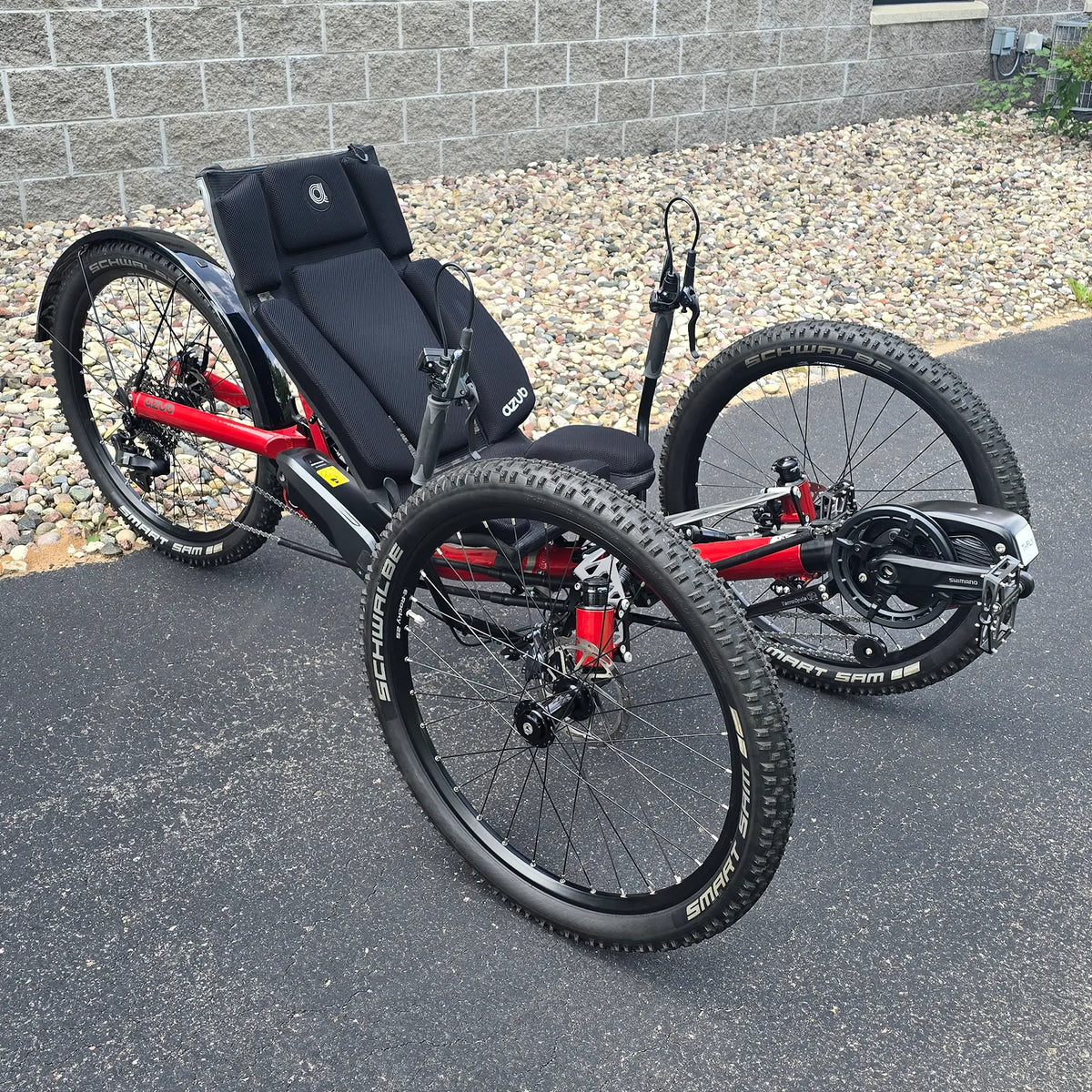 Angled side view of the Azub Demo Ti-Fly X Shimano EP6 Ruby Red Recumbent Trike in an outdoor setting.