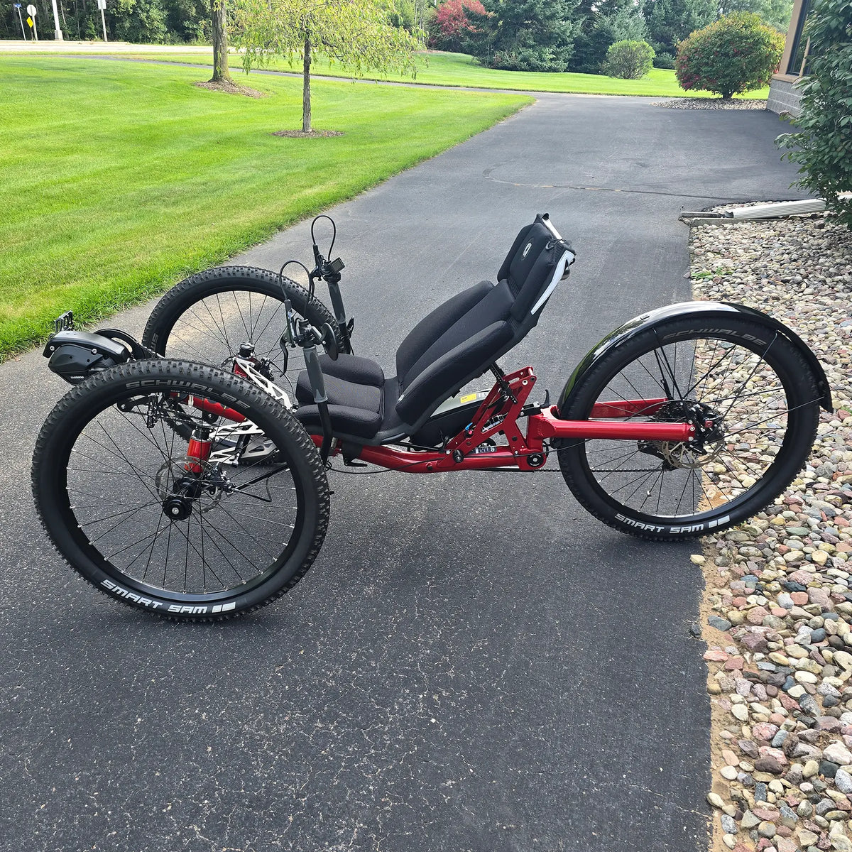 Non-drive side view of the Azub Demo Ti-Fly X Shimano EP6 Ruby Red Recumbent Trike in an outdoor setting.