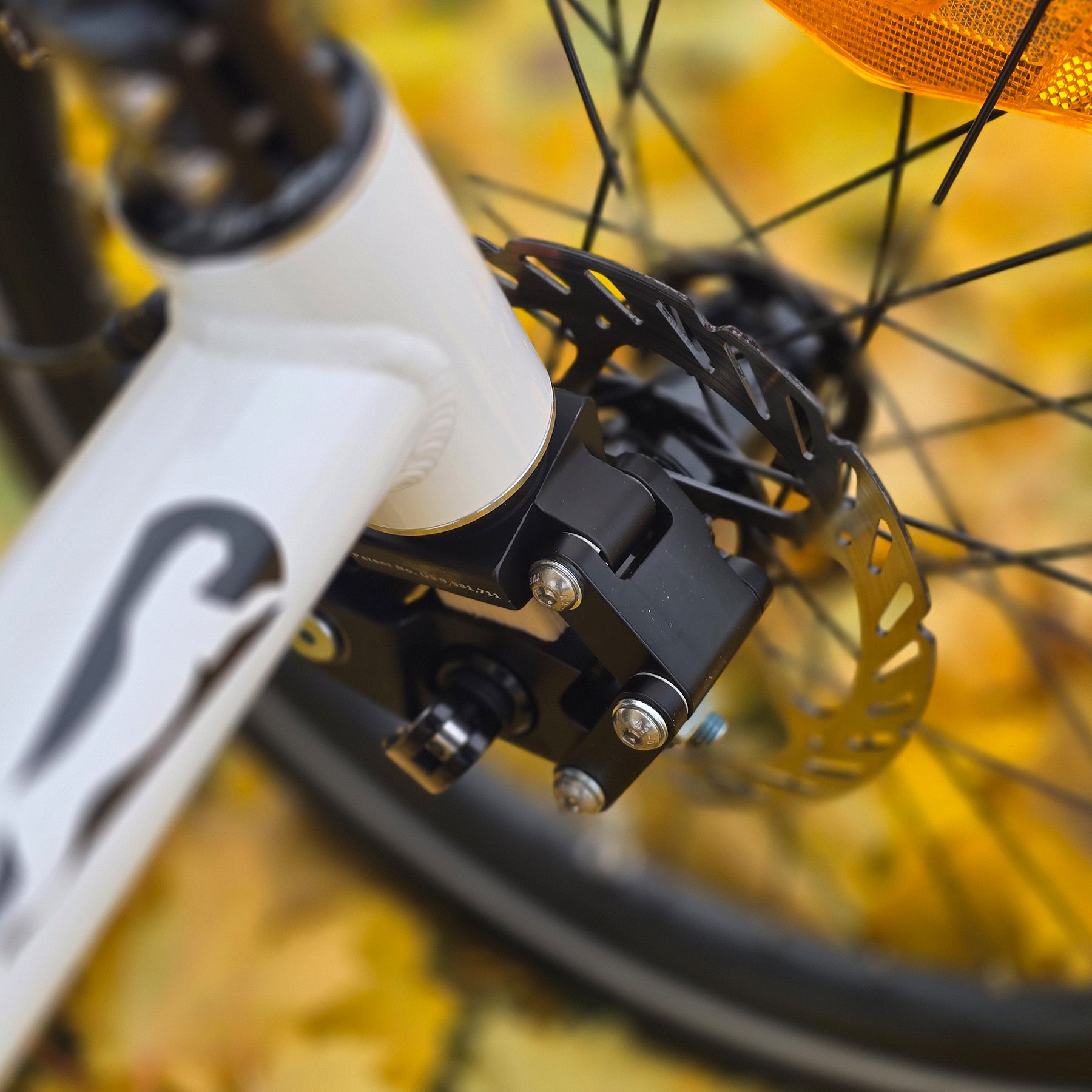 Closeup view of the front shock on the Catrike All Road in Star White in an outdoor setting.