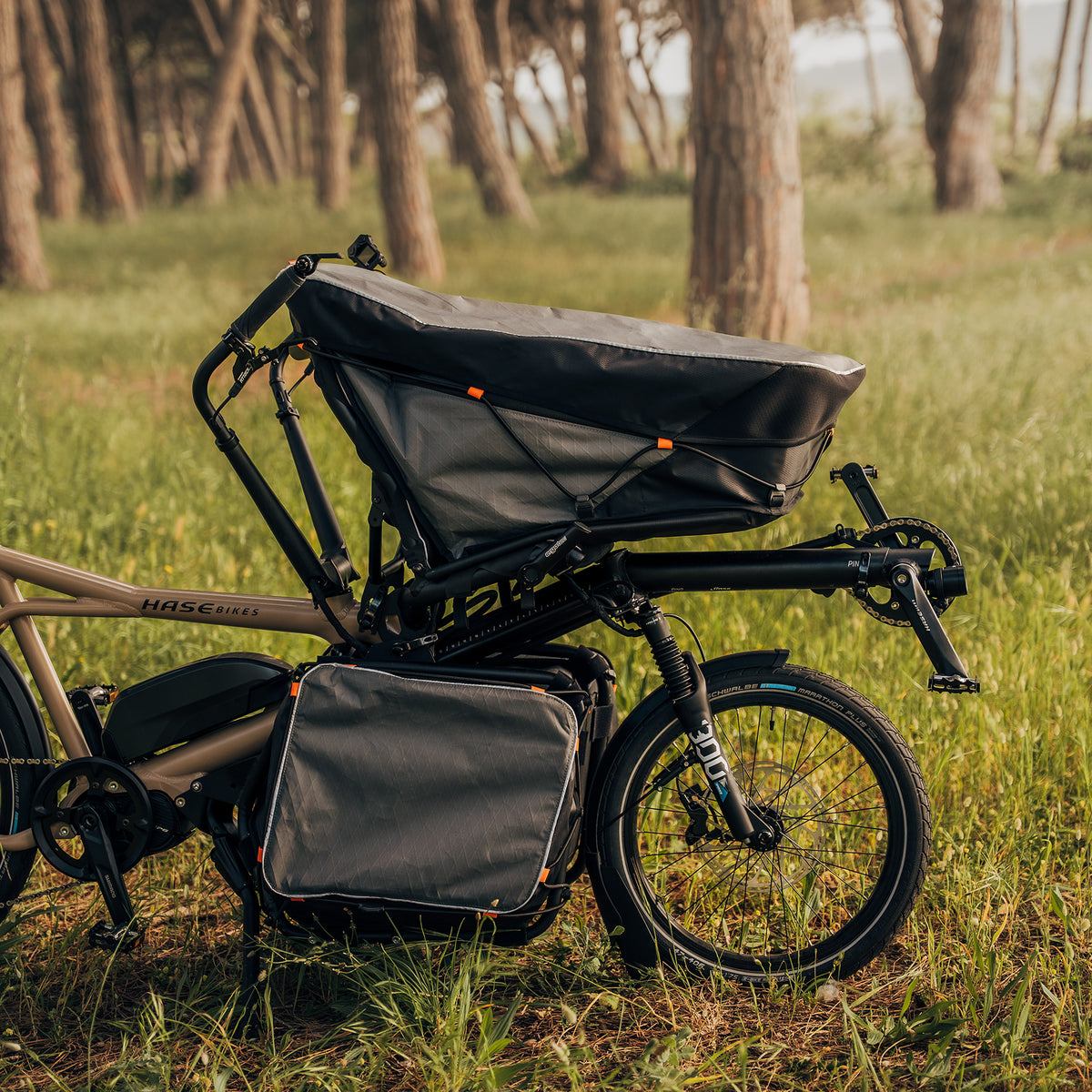Closeup view of the optional cargo bags for the Hase Pino EP6 Cargo Grey Beige Tandem Recumbent Bike in a tree filled grassy setting.