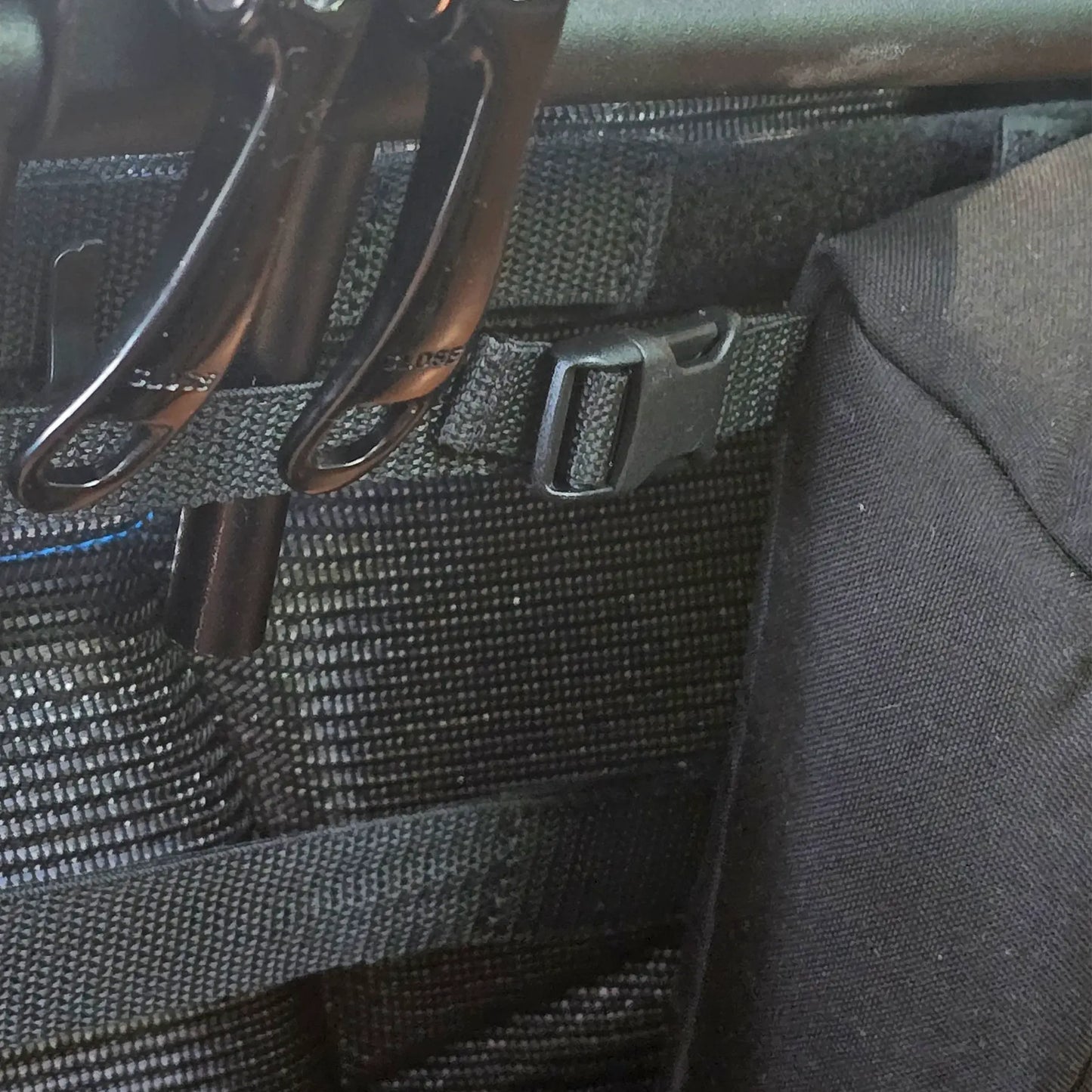 Closeup view of the attachment buckle on the HP Velotechnik Add-On Bags for Mesh Seat in black mounted on a trike.