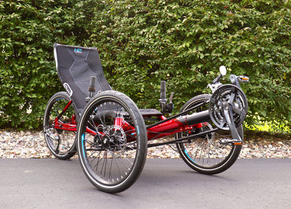Front angled view of the HP Velotechnik Gekko fx 20 Sport Recumbent Trike in Magma on a bike path against a green leafy background.