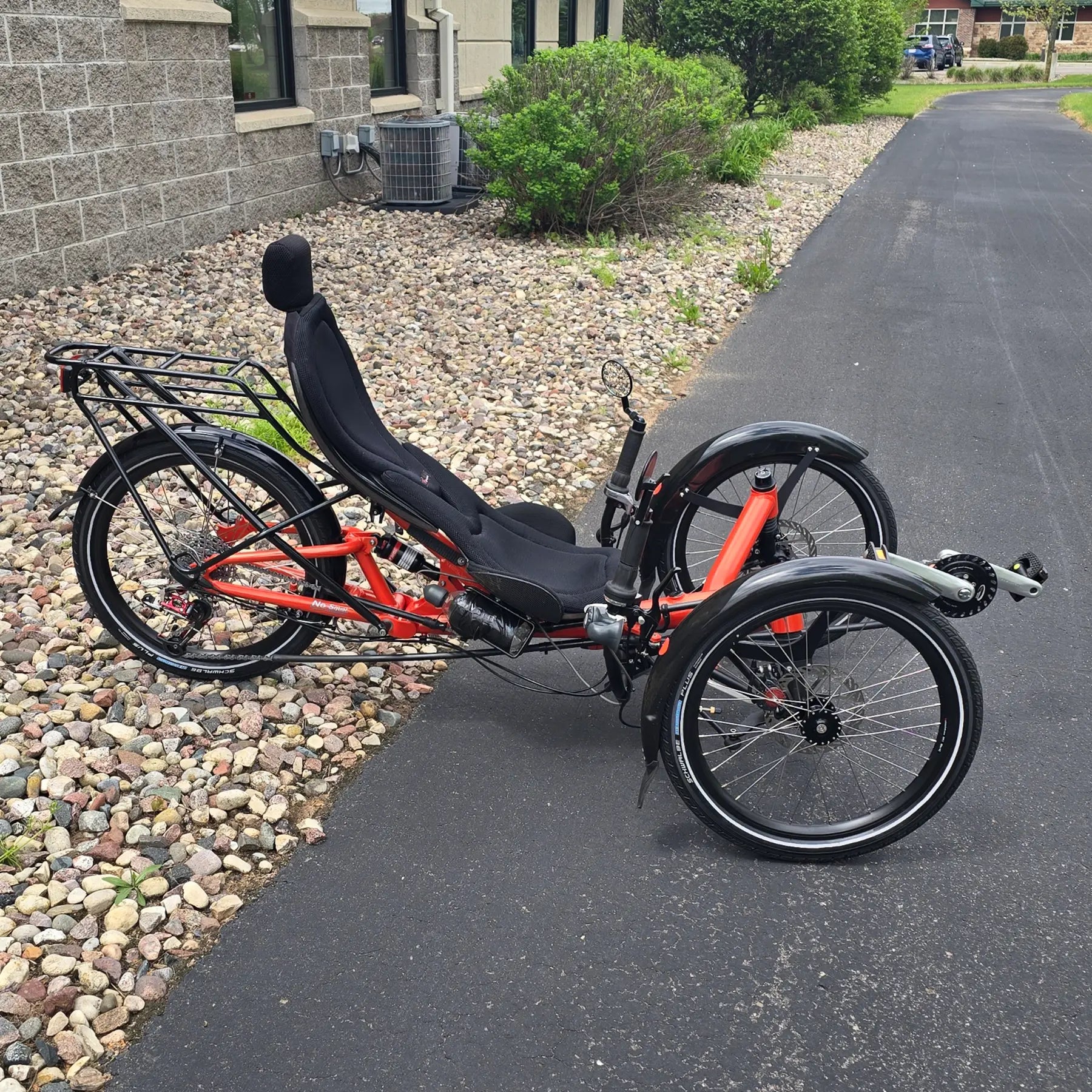 Drive side view of the HP Velotechnik Used Scorpion fs 20 Orange Recumbent Trike in an outdoor setting.