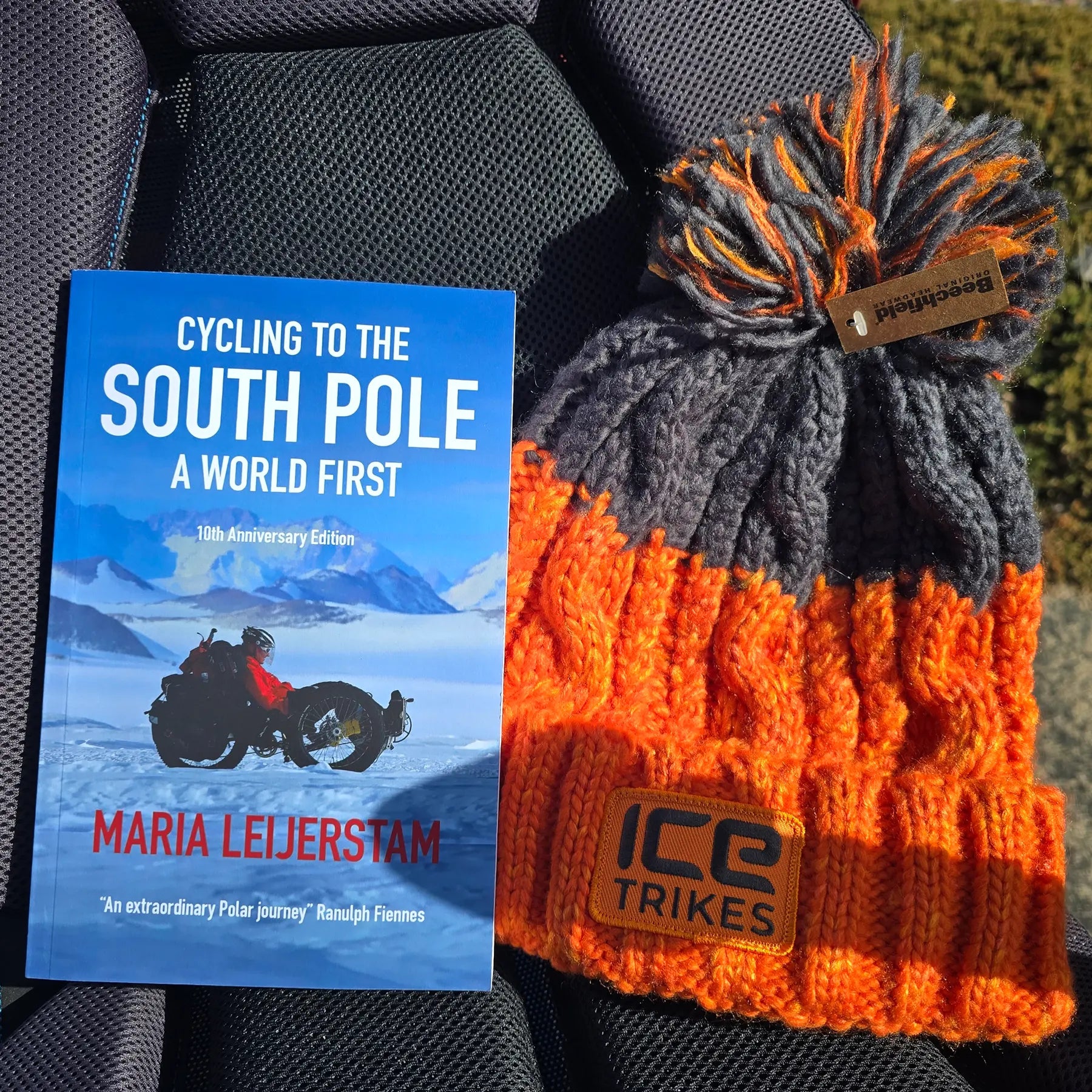 Closeup view of the book and hat included with the ICE Full Fat RS Rohloff Shimano EP8 Hostel Shoppe Limited Edition Custom Blue Recumbent Trike outside in front of the Hostel Shoppe.